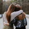 One young woman hugging another